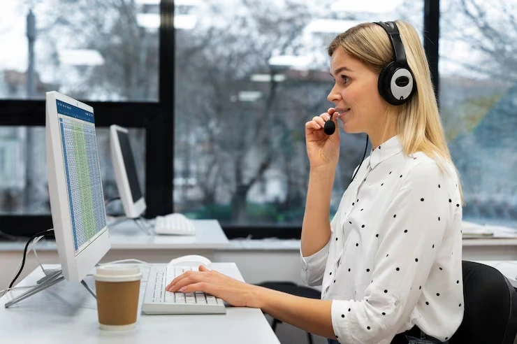 Woman on headset working at computer in office