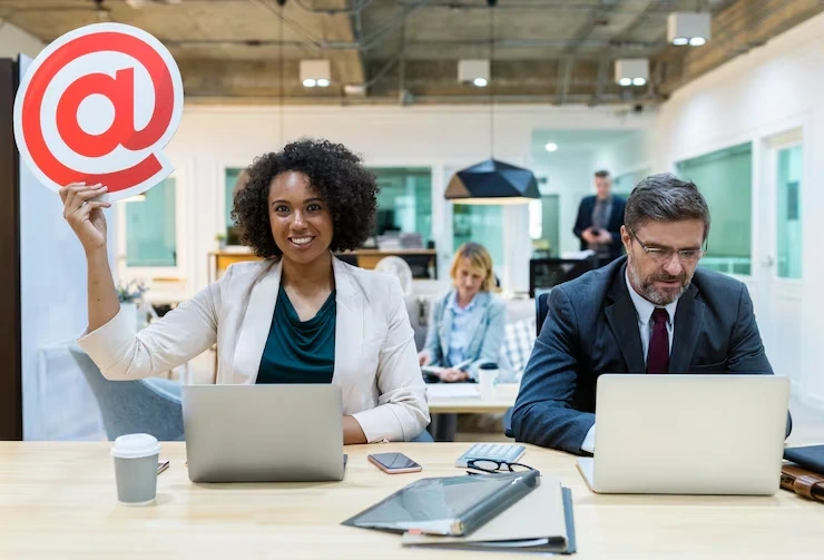 Woman holding email symbol sign at office desk